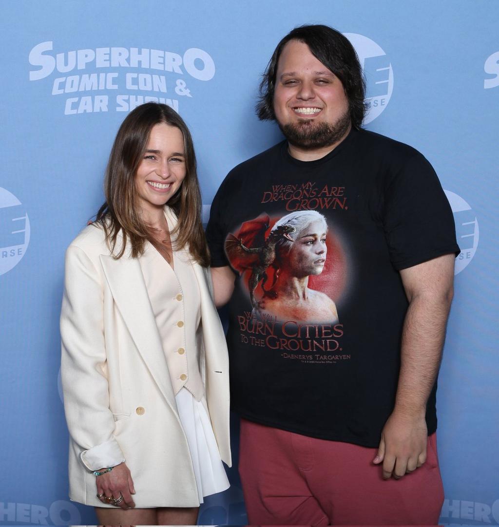 Emilia Clarke posing with a fan at a comic convention